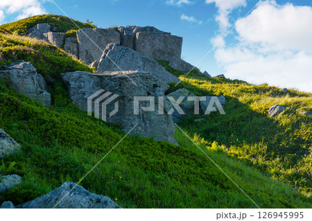 pile of rock boulder on the grassy slope. alpine scenery on mount smooth in transcarpatia. blue sky with clouds 126945995