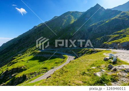 romania travel landscape with road in summer. memorable journey through transylvania alps scenery in morning light. touristic destination of europe. sunny day with blue sky and fluffy clouds romania travel landscape with road in summer. memorable journey through transylvania alps scenery in morning light. touristic destination of europe. sunny day with blue sky and fluffy clouds 126946011