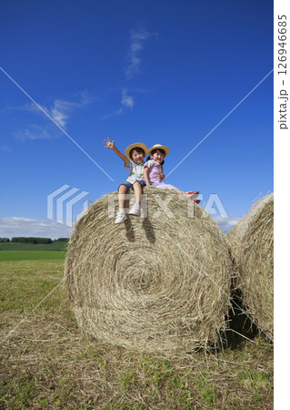 大きな干し草ロールの上に乗る兄妹 126946685