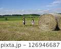 大きな干し草ロールの横を走る兄妹 126946687