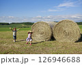 大きな干し草ロールの横を走る兄妹 126946688