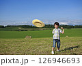 牧草地で麦わら帽子を飛ばして遊ぶ少年 126946693