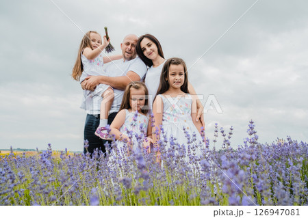A mother in a white dress is hugging her husband, who is holding a cute little girl 126947081