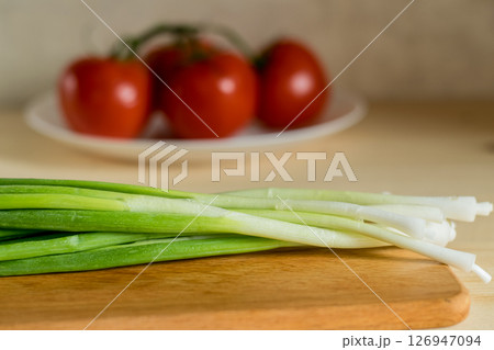 Close-up of young onions on a wooden kitchen board Close-up of young onions on a wooden kitchen board 126947094