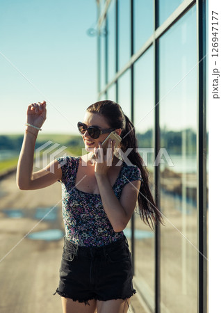 A young woman is talking intently near the transparent panels of the building. 126947177