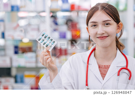 Happy Doctor Pharmacist in drug store hand holding medicine capsule pills pack, Medicare service Happy Doctor Pharmacist in drug store hand holding medicine capsule pills pack, Medicare service 126948847