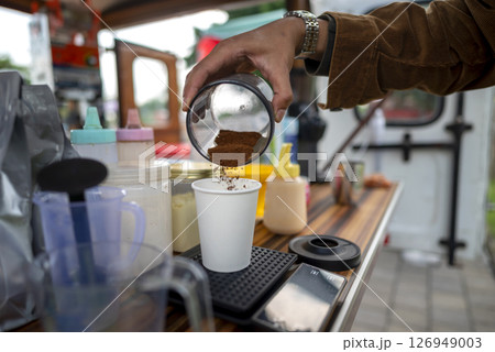 Male barista serving coffee at a table. A small business of a coffee shop or cafe on a truck Male barista serving coffee at a table. A small business of a coffee shop or cafe on a truck 126949003
