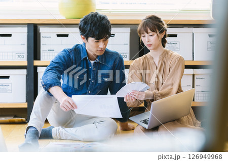 オフィスの床に座って仕事をする男女 オフィスの床に座って仕事をする男女 126949968
