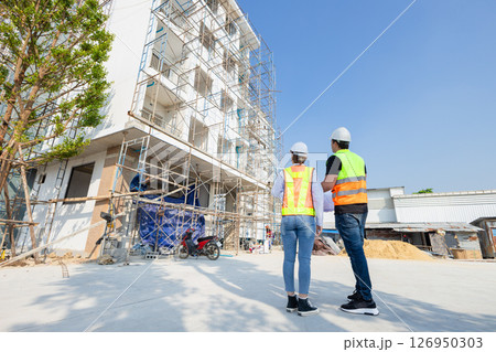 back view construction Engineer, architect working together at construction site. construction worker planning at construction site. back view construction Engineer, architect working together at construction site. construction worker planning at construction site. 126950303