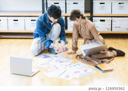 オフィスの床に座って仕事をする男女 オフィスの床に座って仕事をする男女 126950362