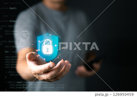 A person holds a glowing digital shield with a lock icon, symbolizing cyber security and data protection, surrounded by hexagonal patterns and soft futuristic lighting. A person holds a glowing digital shield with a lock icon, symbolizing cyber security and data protection, surrounded by hexagonal patterns and soft futuristic lighting. 126950459