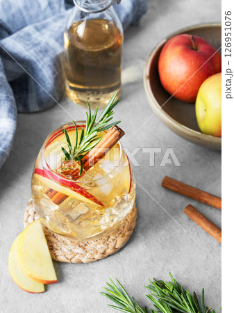 Apple cocktail or cider  with ice, garnished with cinnamon and rosemary  in a glass  126951076