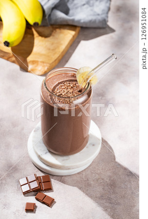 Vegetarian chocolate smoothie with banana in a glass on a light background with fruis Vegetarian chocolate smoothie with banana in a glass on a light background with fruis 126951084