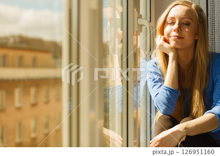 Woman relaxing on windowsill 126951160