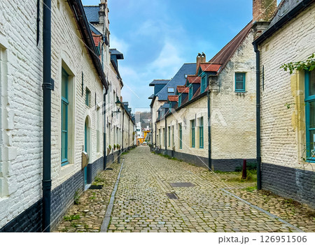 Charming cobblestone street in historic area surrounded by quaint white brick houses 126951506