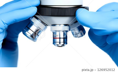 Close-up shot of a microscope lens adjusted by hands in surgical gloves 126952012