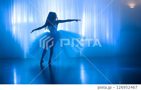 Graceful Ballet Dancer Performing Silhouette Against a Blue Lit Stage 126952467
