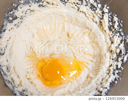 Beating butter, sugar and eggs in a grey metal bowl. The process of making cake and cookies by mixing butter, eggs and sugar. 126953000