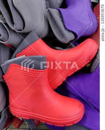 bright rubber boots in various colors displayed on retail shelf options for rainy weather. closeup. bright rubber boots in various colors displayed on retail shelf options for rainy weather. closeup. 126953678