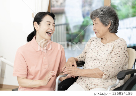 車椅子のシニア女性と話をする女性介護士 車椅子のシニア女性と話をする女性介護士 126954189