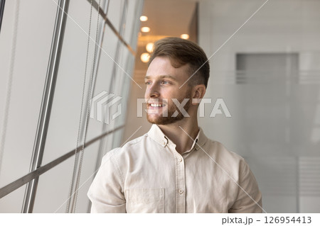 Handsome millennial businessman posing alone in modern workspace Handsome millennial businessman posing alone in modern workspace 126954413