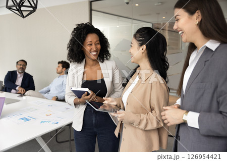 Three multiethnic professional businesswomen engaging in cheerful conversation 126954421