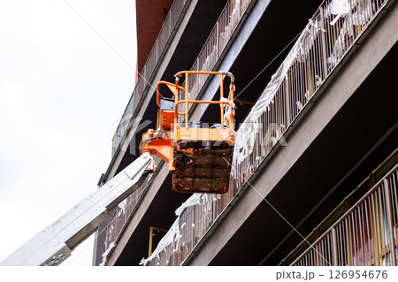 A very large orange bucket can be seen attached to the side of a building 126954676