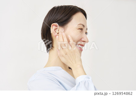 補聴器を使う40代の女性 白背景 補聴器を使う40代の女性 白背景 126954862