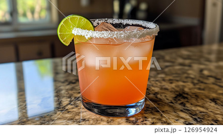 Classic margarita cocktail with salted rim, lime wedge and ice in a glass on a marble countertop Classic margarita cocktail with salted rim, lime wedge and ice in a glass on a marble countertop 126954924