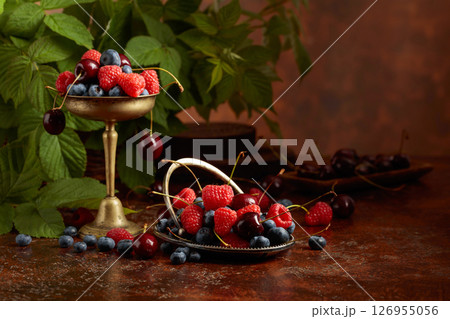 Berries with leaves on an old brown table. 126955056
