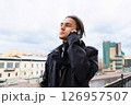 young man talking on smartphone or phone standing on balcony in european city 126957507