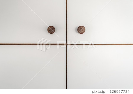 White cabinet doors of wooden closet with wooden knobs close-up as modern design backdrop 126957724