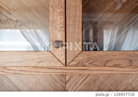 Elegant oak cabinet featuring glass doors and wooden knobs close view Elegant oak cabinet featuring glass doors and wooden knobs close view 126957726