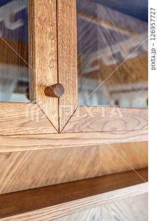 Elegant oak cabinet featuring glass doors and wooden knobs close view Elegant oak cabinet featuring glass doors and wooden knobs close view 126957727