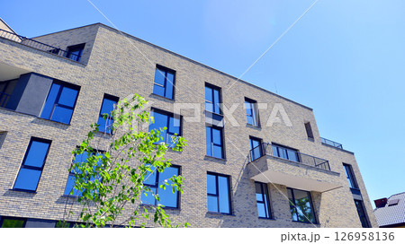Eco architecture. Green tree and new residential building. Harmony of nature and modernity. Modern apartment building with new apartments in a green residential area. Eco architecture. Green tree and new residential building. Harmony of nature and modernity. Modern apartment building with new apartments in a green residential area. 126958136