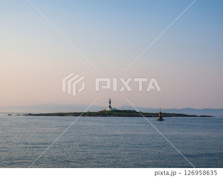 海に浮かぶ小島と灯台　夕暮れの空と静かな海の風景 126958635