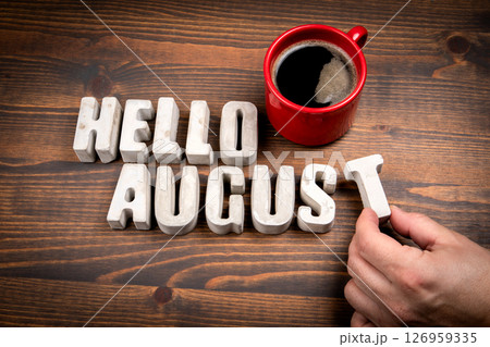 Hello August. Concrete alphabet letters and coffee mug on dark wooden texture background 126959335