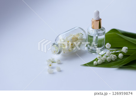 Glass bottle of lily of the valley essential oil with fresh flowers 126959874