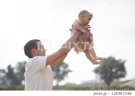 Happy dad throws up with his little daughter for a walk. Paternity. 126961546
