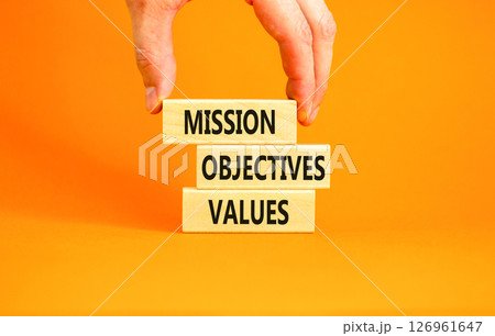 Mission objectives values symbol. Concept words Mission Objectives Values on beautiful blocks. Beautiful orange background. Businessman hand. Business mission objectives values concept. Copy space. 126961647