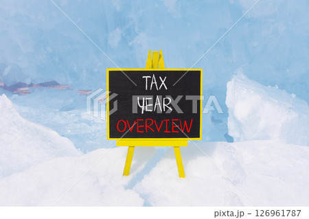 Tax year overview symbol. Concept words Tax year overview on beautiful black yellow blackboard. Beautiful blue Baikal ice background. Business tax year overview concept. Copy space. Tax year overview symbol. Concept words Tax year overview on beautiful black yellow blackboard. Beautiful blue Baikal ice background. Business tax year overview concept. Copy space. 126961787