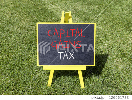 Capital gains tax symbol. Concept words Capital gains tax on beautiful yellow blackboard. Beautiful green grass lawn background. Business and capital gains tax concept. Copy space. 126961788