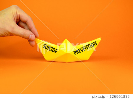 Suicide prevention symbol. Concept words Suicide prevention on beautiful yellow paper boat. Beautiful orange background. Psychologist hand. Psychological and suicide prevention concept. Copy space. Suicide prevention symbol. Concept words Suicide prevention on beautiful yellow paper boat. Beautiful orange background. Psychologist hand. Psychological and suicide prevention concept. Copy space. 126961853