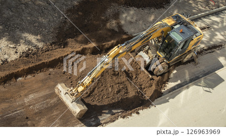 yellow excavator digging a hole at a construction site top view 126963969