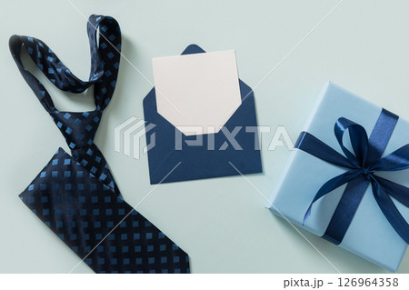Happy Fathers Day. Greeting card with blue gift, tie, empty white sheet with copy space on light blue background. Men's accessories set. Top view. Copy space. Happy Fathers Day. Greeting card with blue gift, tie, empty white sheet with copy space on light blue background. Men's accessories set. Top view. Copy space. 126964358