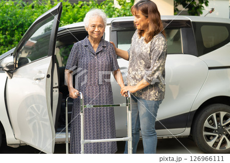 Caregiver help Asian elderly woman disability patient get in her car. Caregiver help Asian elderly woman disability patient get in her car. 126966111