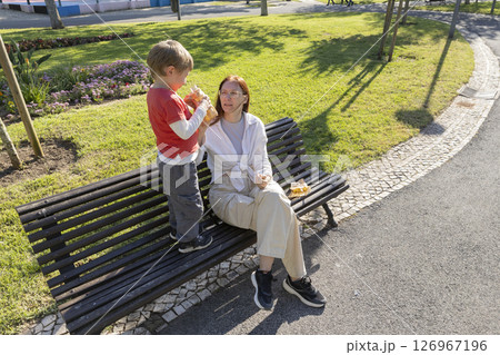 Child sharing juice with grandmother on park bench Child sharing juice with grandmother on park bench 126967196