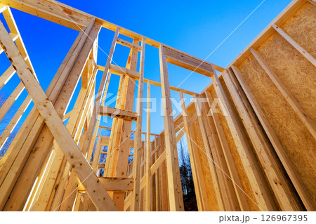 Builders are assembling wooden beams frames for new house at construction zone Builders are assembling wooden beams frames for new house at construction zone 126967395
