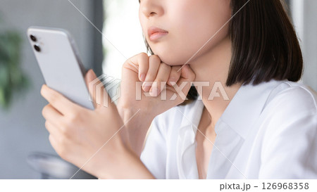 スマートフォンを持って考えごとをする女性 スマートフォンを持って考えごとをする女性 126968358