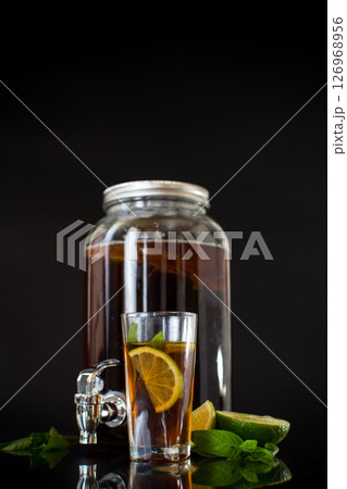 Refreshing kombucha in a glass jar and a glass with lime on a black background Refreshing kombucha in a glass jar and a glass with lime on a black background 126968956